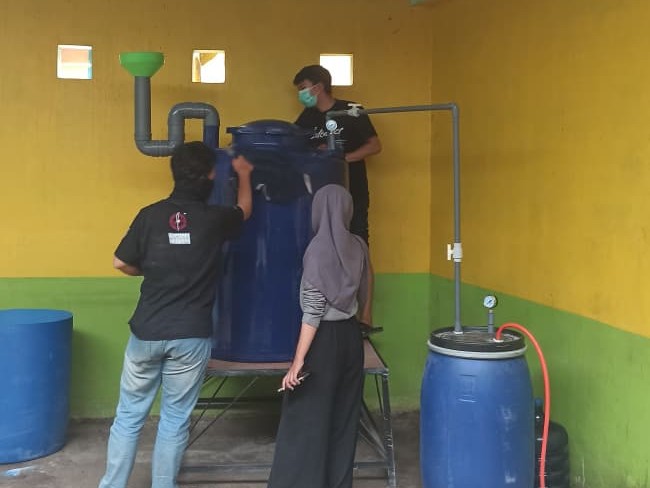 Students working on the installation of a biodigester system at Mulyoagung TPST 3R.