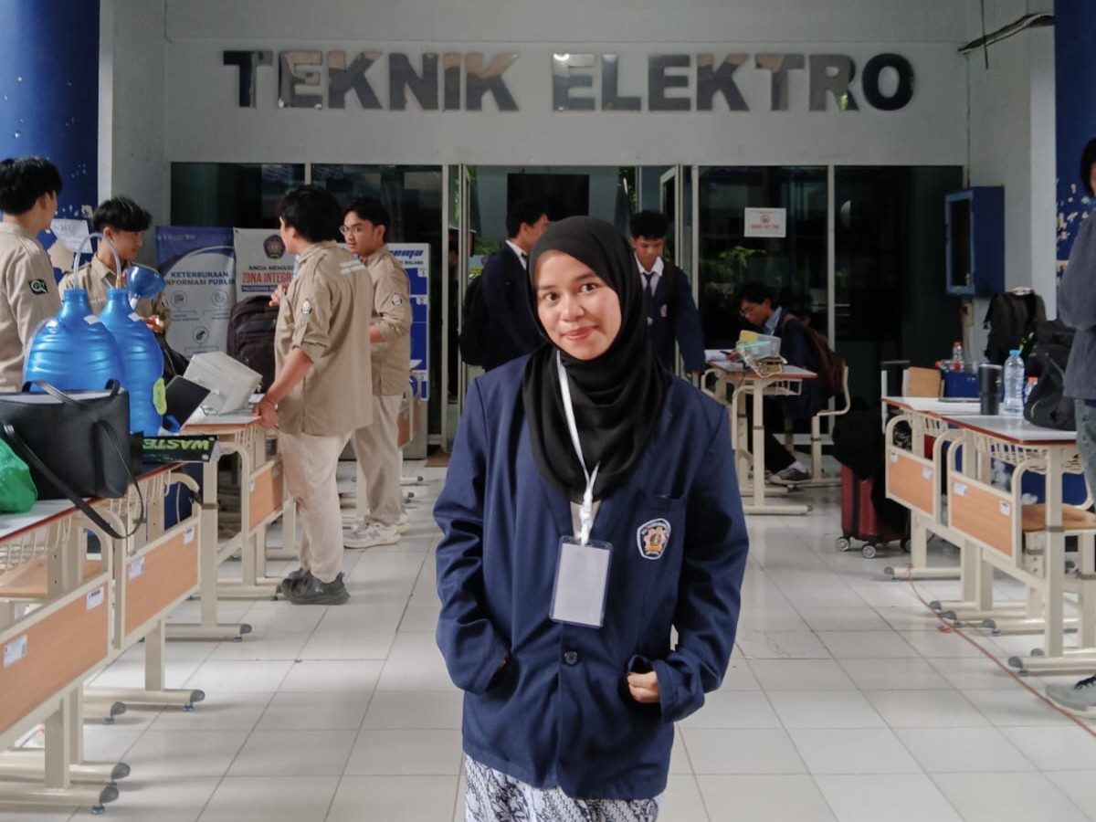 Participating in the LOGRAK National Competition 2025 Photo of a participant during the LOGRAK National Competition 2025 exhibition at Politeknik Negeri Malang, with other competition teams and exhibition displays in the background.